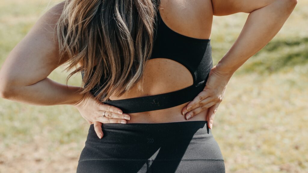 woman in black activewear placing hands behind back